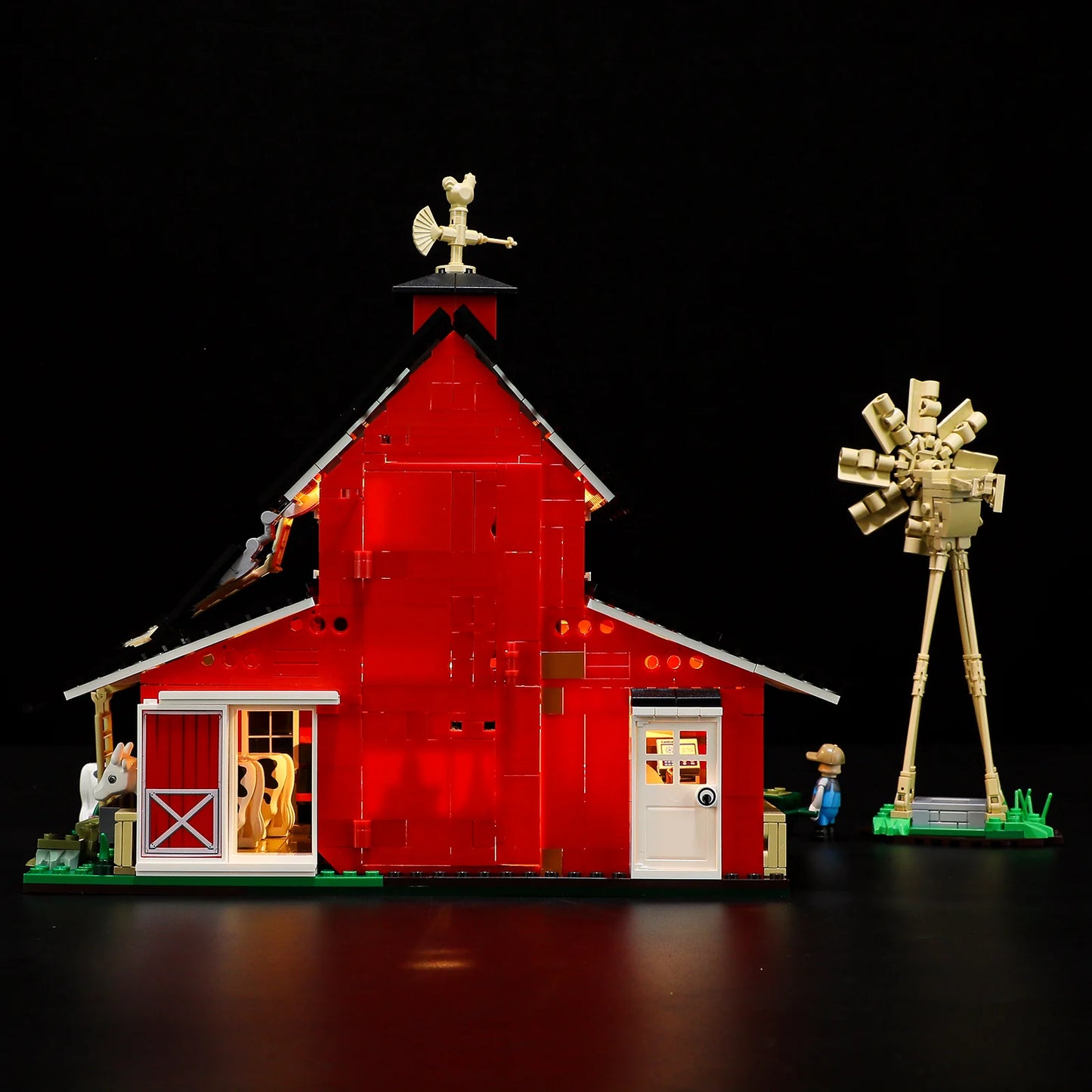 Lumibricks F9037 Cow Barn side view at night with red barn, illuminated windows, tan windmill, and farmer minifigure