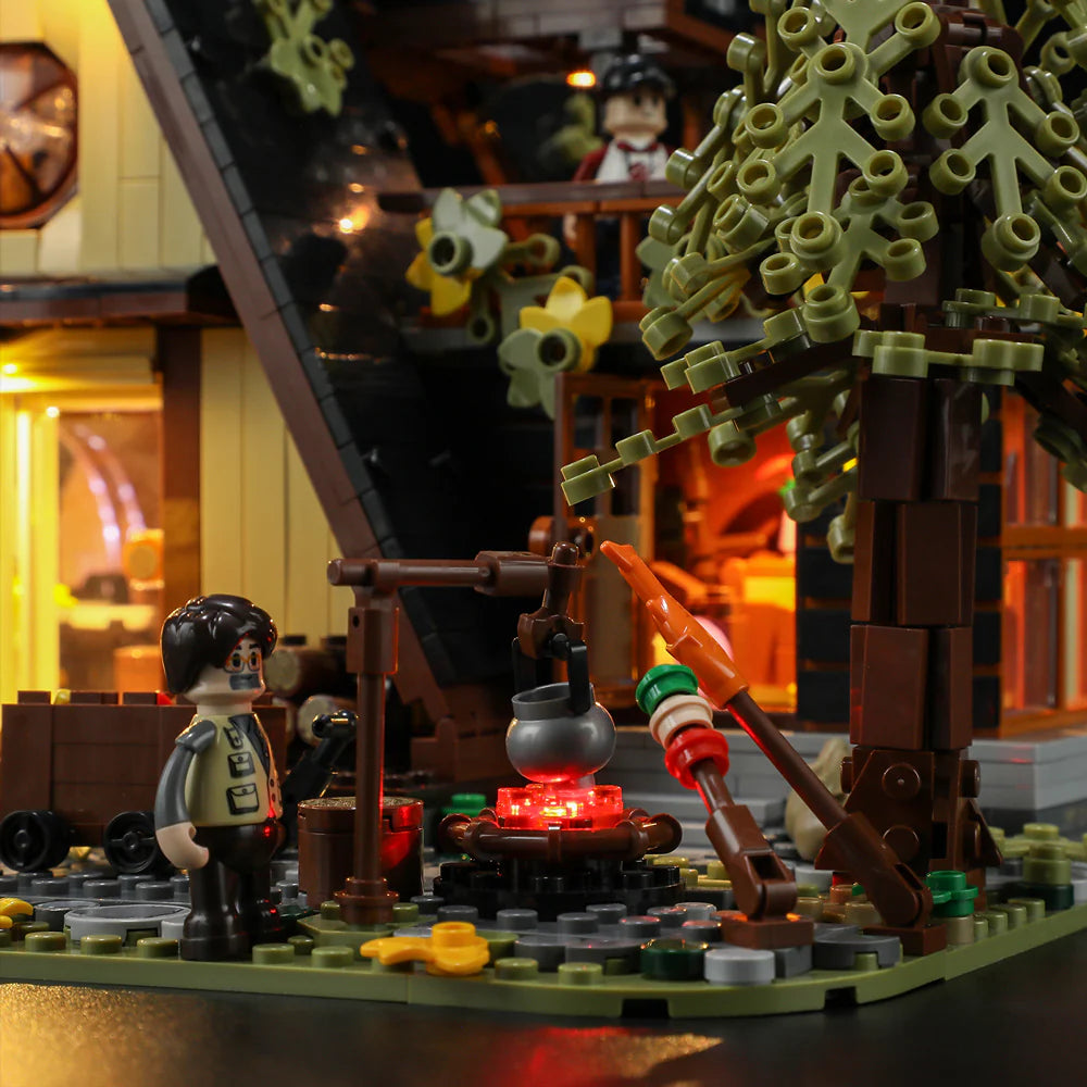 Funwhole A-Frame Cabin set featuring a cozy outdoor campfire scene with a minifigure, cooking pot, and warm glowing lights