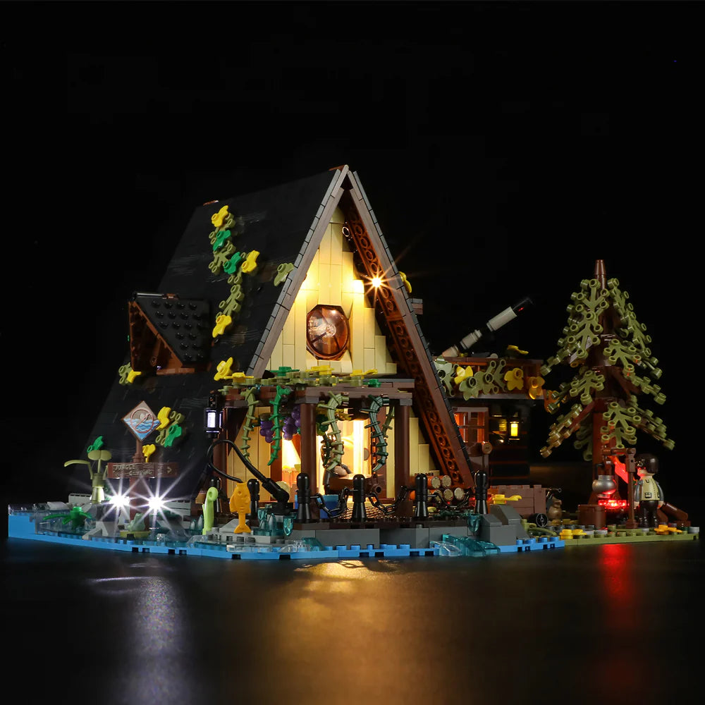 Funwhole A-Frame Cabin LEGO set at night with glowing lights, detailed scenery, lake, trees, and minifigures in a cozy setup