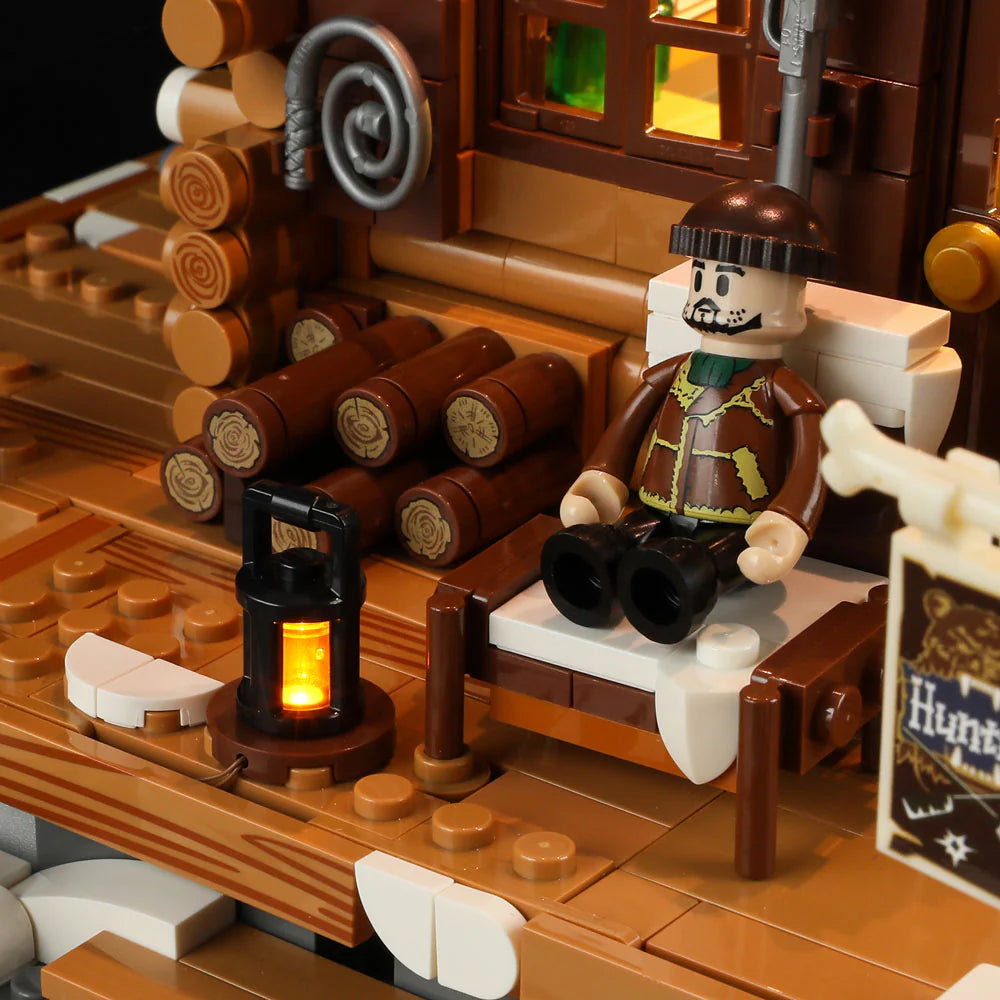 Funwhole Hunting Cabin set with a hunter figure relaxing on the porch, a glowing lantern, stacked logs, and rustic wooden details