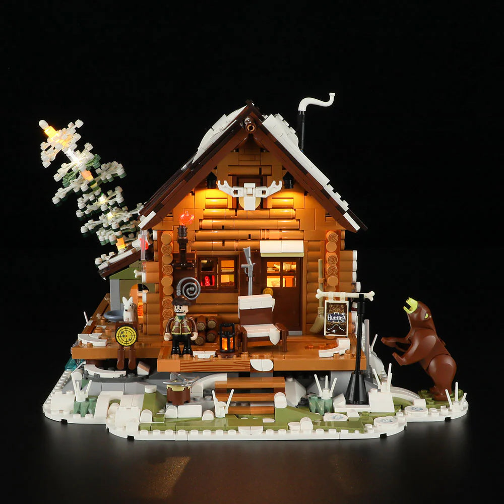 Front view of Funwhole Hunting Cabin set with LED lights, a rustic log cabin, snowy landscape, and a bear figure at night
