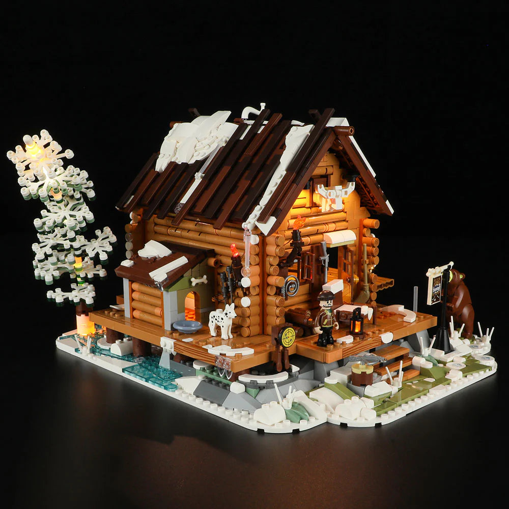 Funwhole Hunting Cabin set illuminated at night, showcasing a cozy log cabin, snowy scenery, LED lights, and winter wildlife