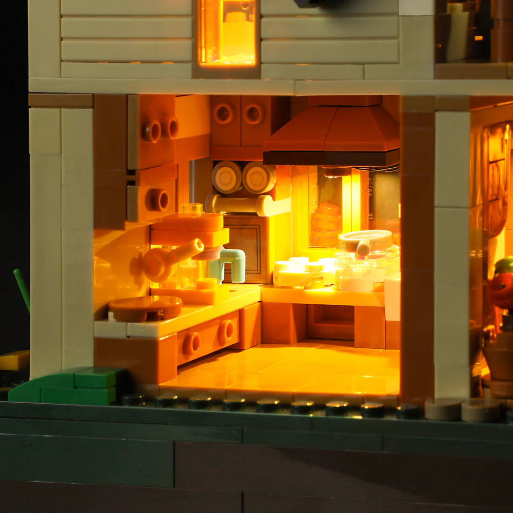 Illuminated kitchen interior of Funwhole Lakeside Lodge set, featuring cabinets, sink, stove, and cozy lighting details