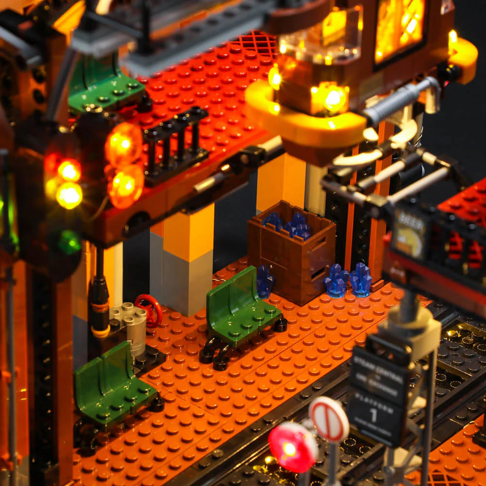 Lumibricks F9007 Steampunk Train Station front view at night with illuminated clock tower, gears, and platform