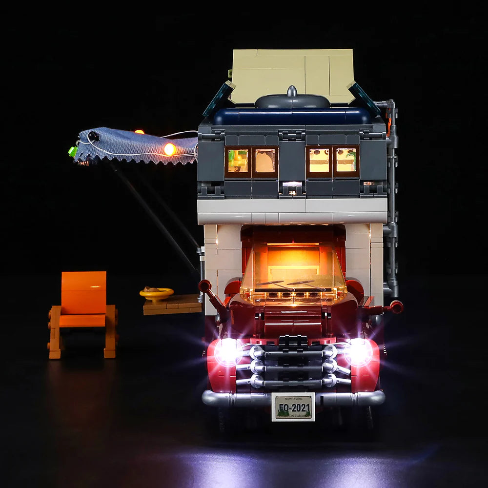 Lumibricks F9012 Camper Van front view at night with bright LED headlights, chair, and open door