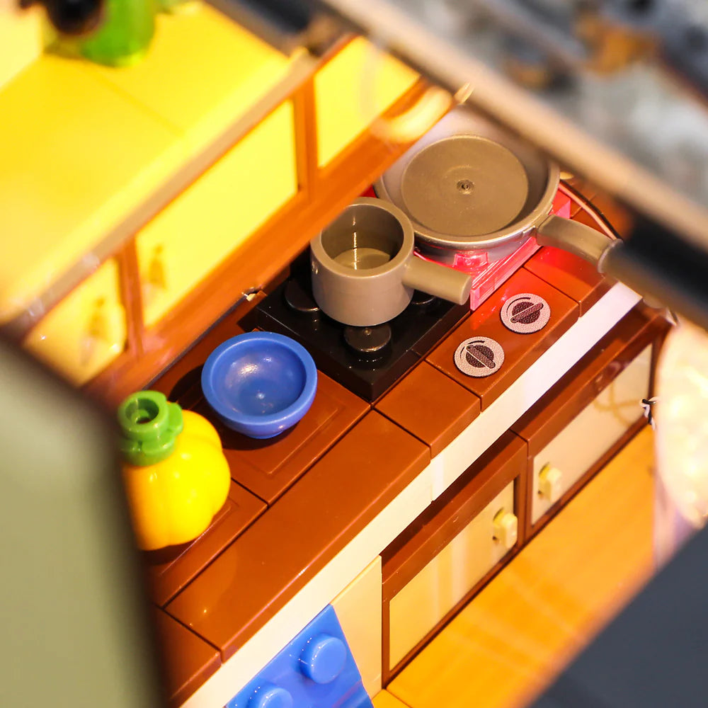 Lumibricks F9012 Camper Van kitchen with stove, pan, mug, blue bowl, pumpkin, and glowing countertop lights