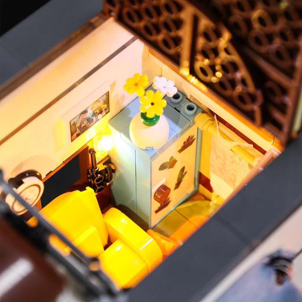 Lumibricks F9012 Camper Van living area with yellow sofa, blue fridge, flower vase, wall art, and warm lighting