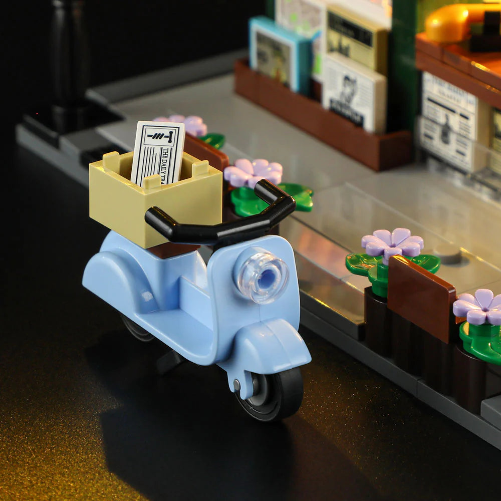 Lumibricks F9023 Newsstand close-up of blue scooter with newspaper delivery box, flowers, and magazine racks on city sidewalk