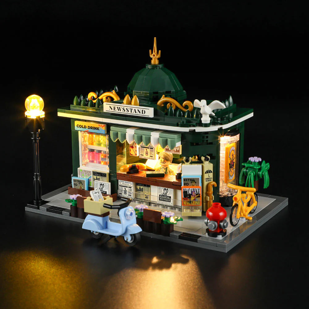Lumibricks F9023 Newsstand top angle at night with glowing lights, minifigure vendor, scooter, and yellow bicycle outside
