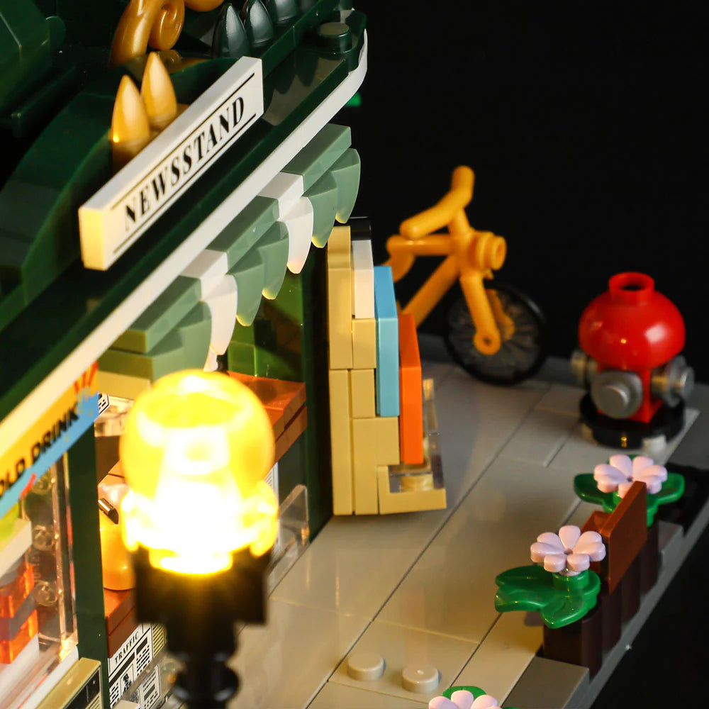 Lumibricks F9023 Newsstand sidewalk with yellow bicycle, red fire hydrant, illuminated lamp post, and flower beds