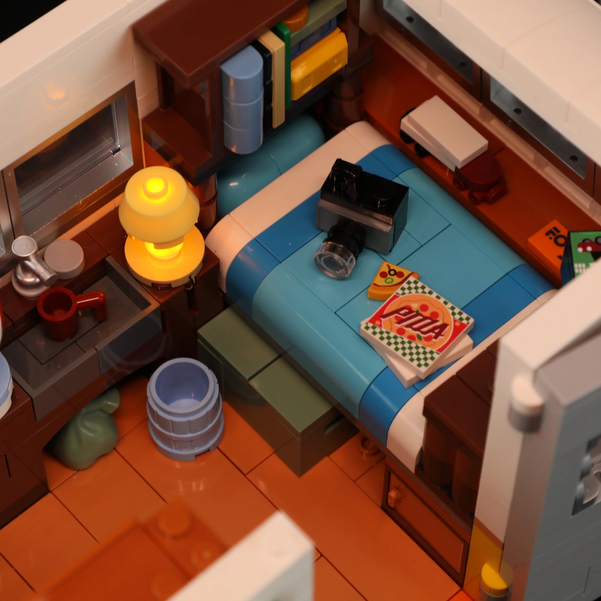 Lumibricks F9032 Travel Trailer bedroom with blue bed, pizza box, camera, glowing lamp, and storage shelves
