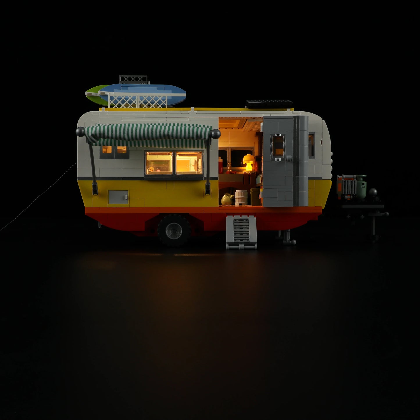 Lumibricks F9032 Travel Trailer side view at night with illuminated windows, striped awning, and glowing interior