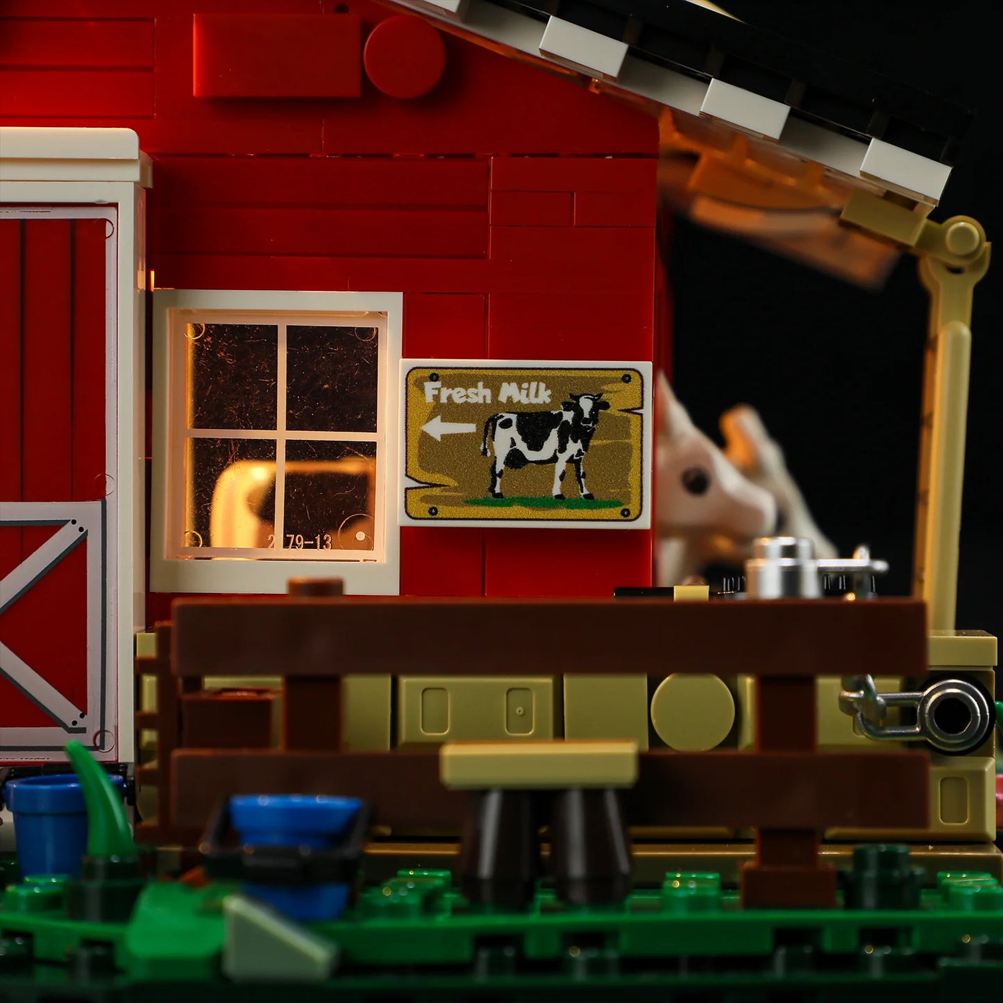 Lumibricks F9037 Cow Barn close-up of "Fresh Milk" sign, cow stall, blue bucket, and brown fence with barn window at night
