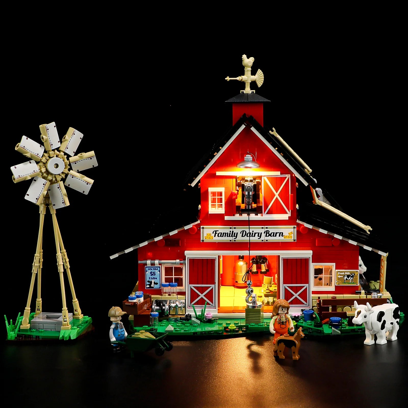 Lumibricks F9037 Cow Barn front view at night with illuminated barn interior, windmill, cows, and farm minifigures