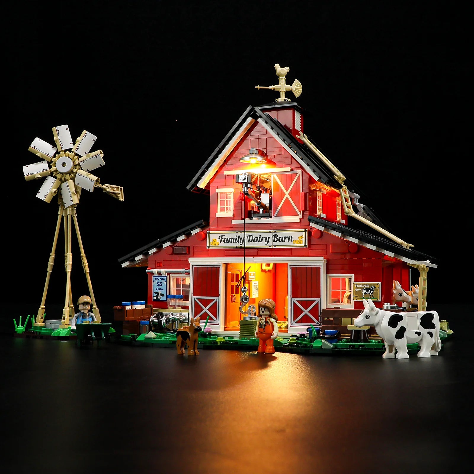 Lumibricks F9037 Cow Barn illuminated at night with glowing barn interior, windmill, cows, and minifigures in farmyard