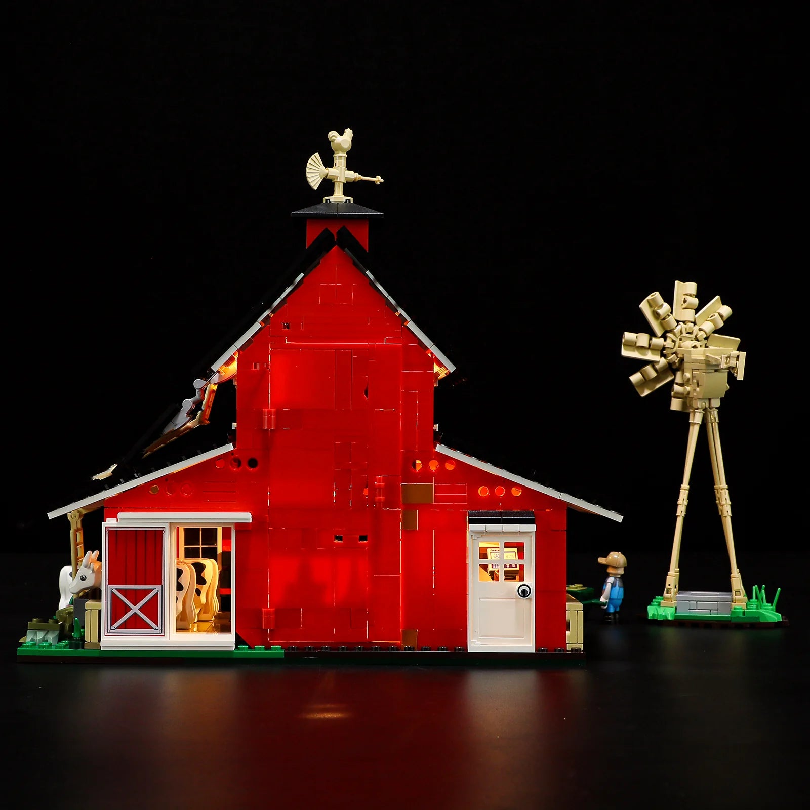 Lumibricks F9037 Cow Barn side view at night with red barn, illuminated windows, tan windmill, and farmer minifigure