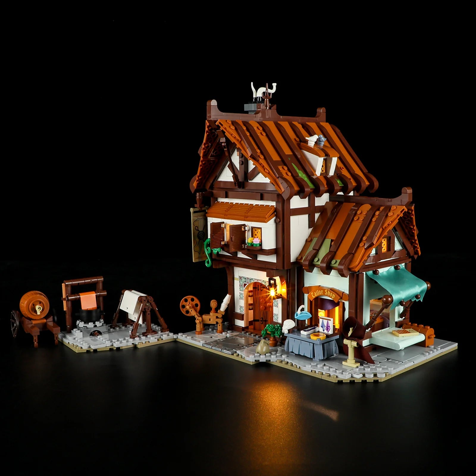 Lumibricks F9038 Medieval Tailor Shop angled night view with illuminated tailor shop, fabric table, and medieval cart