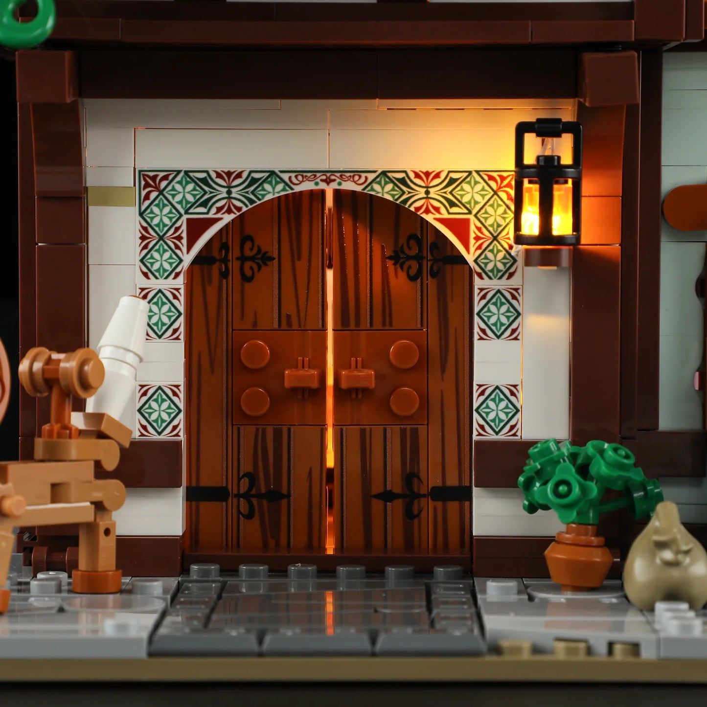 Lumibricks F9038 Medieval Tailor Shop arched wooden door with glowing lantern, tiled arch, and potted plant at night