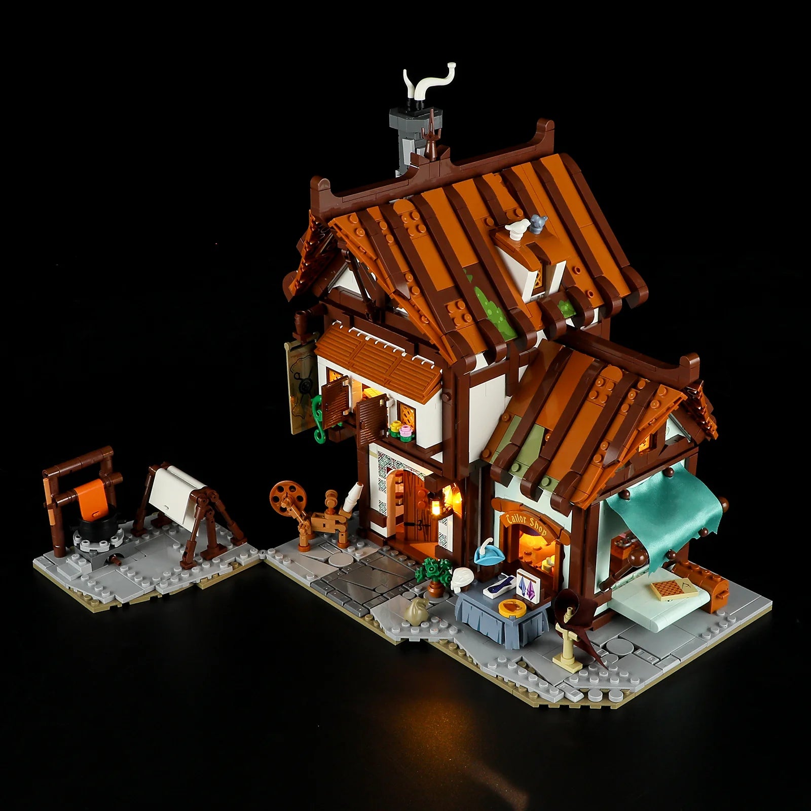 Lumibricks F9038 Medieval Tailor Shop exterior with illuminated windows, market stall, and sewing station at night